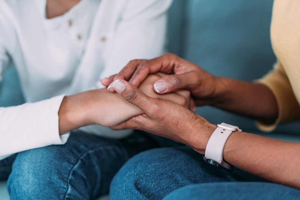 Two people holding hands for support.