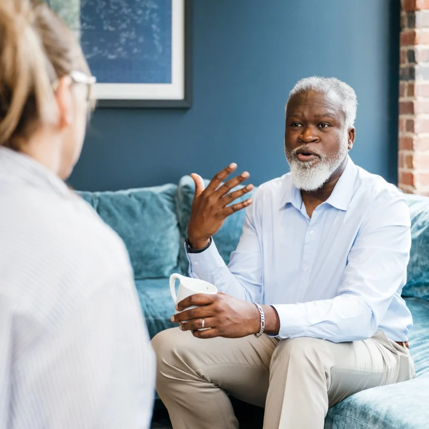 Two people talking on a blue sofa.